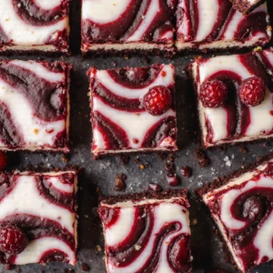 Red velvet cheesecake brownies with creamy cheesecake swirl baked into fudgy red velvet brownie squares.