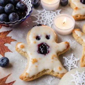 Vegan blueberry ghost hand pies shaped like spooky ghosts, baked golden brown with blueberry filling.